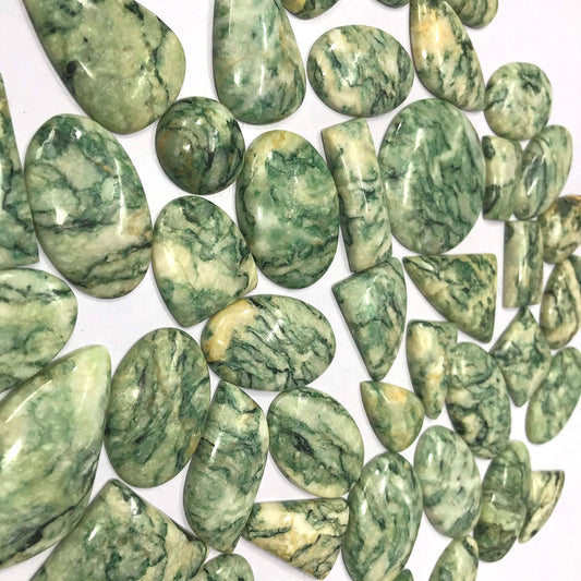 Close up of natural green Mariposite cabochon showing chromium mica pattern flat back polished