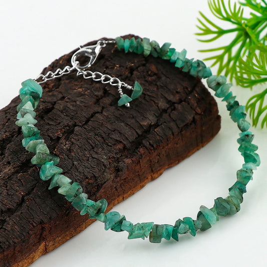 Green beaded bracelet on a wooden block with a green leafy background