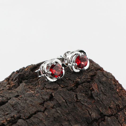 Garnet earrings placed on raw stone showing natural red color