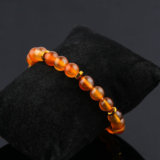 Orange beaded bracelet on a black cushion with a dark background