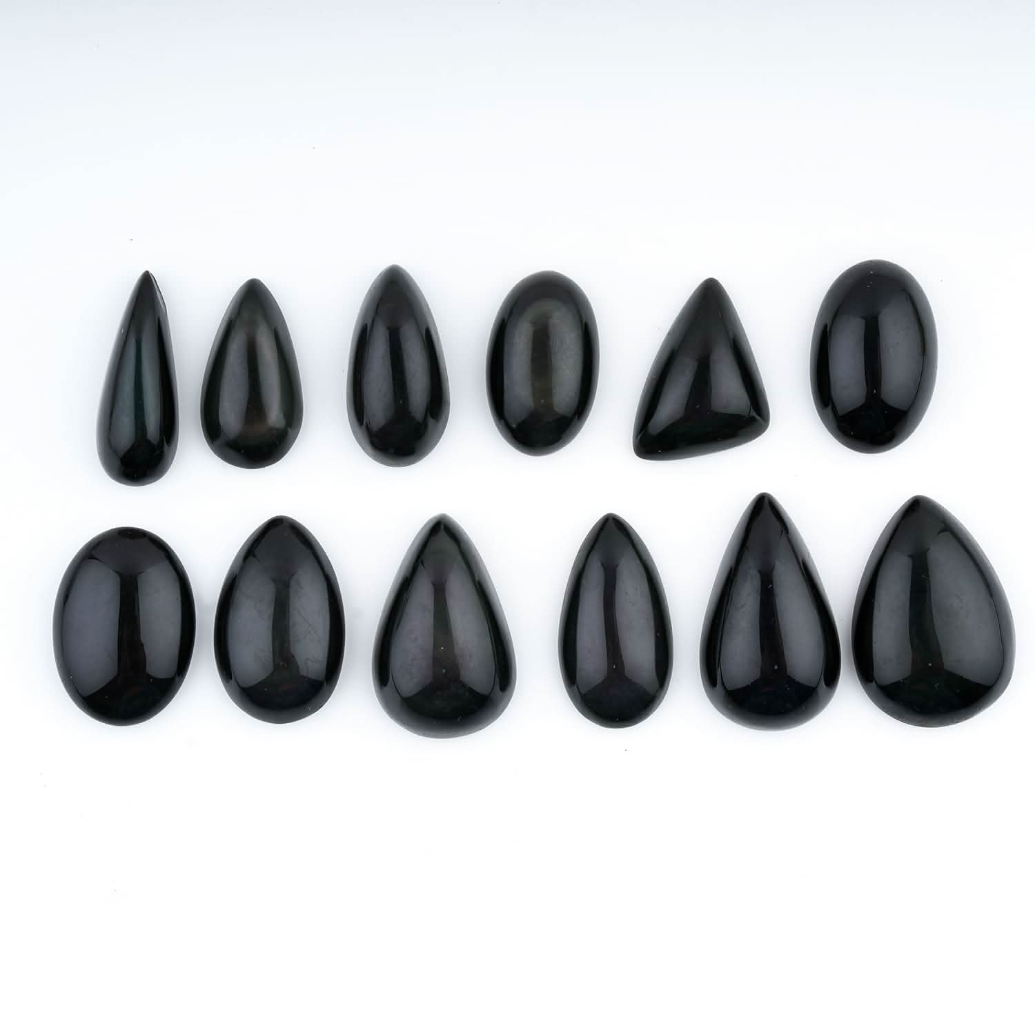 Set of black teardrop-shaped stones on a white background