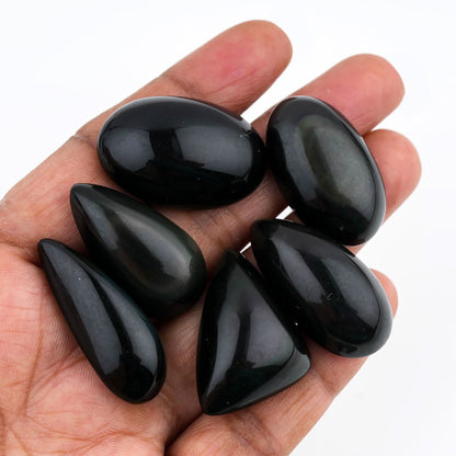Hand holding five black stones against a white background