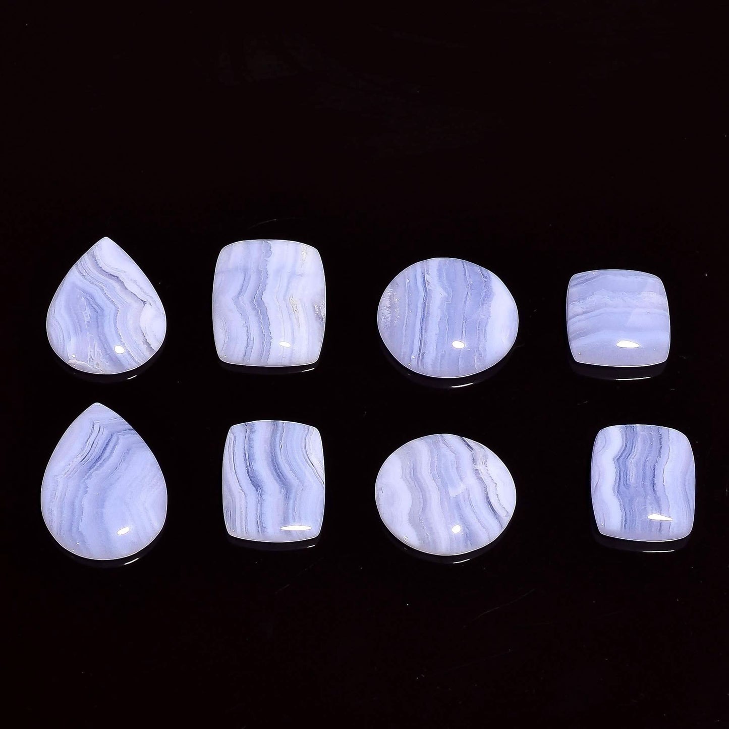 Blue lace agate cabochon lot polished flat back on dark wood surface – lace banding texture detail
