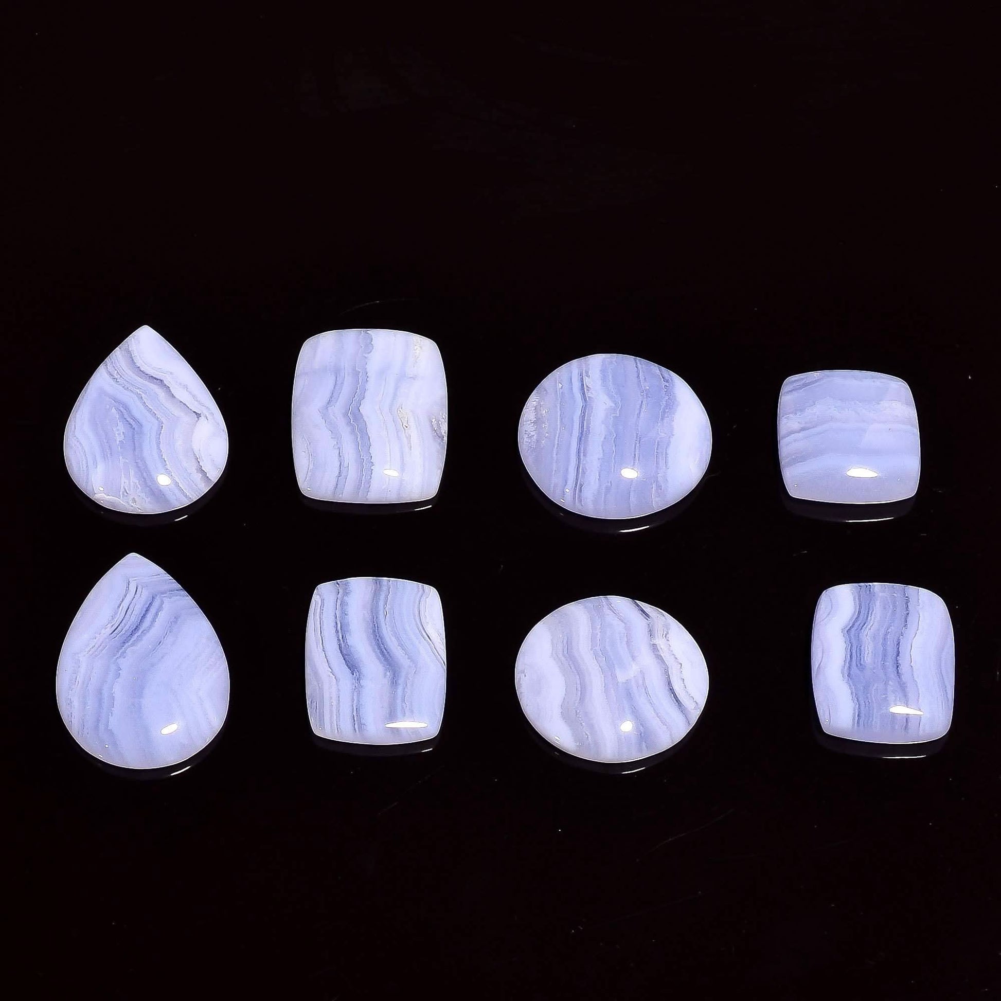 Blue lace agate cabochon lot polished flat back on dark wood surface – lace banding texture detail