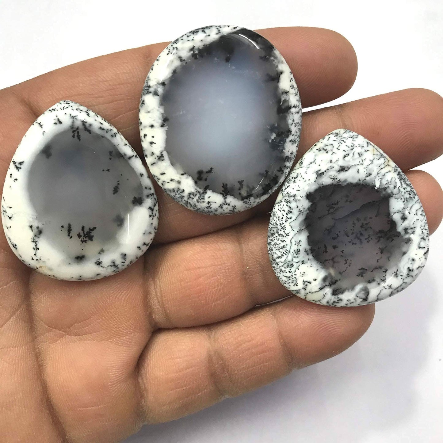 Wholesale dendrite opal stones 20–35mm held in hand – size reference black white pattern