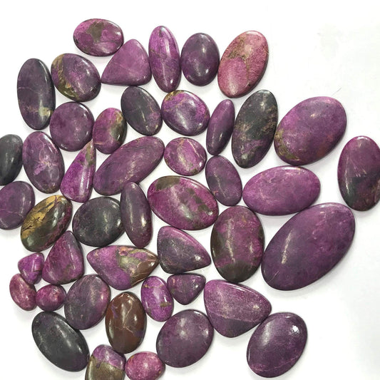 Natural purpurite gemstone cabochons pile – vivid purple pink with dark patches mixed sizes