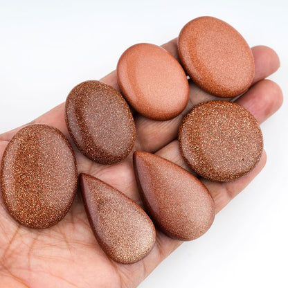 sunstone for jewelry makin, Hand holding a collection of brown stones against a white background