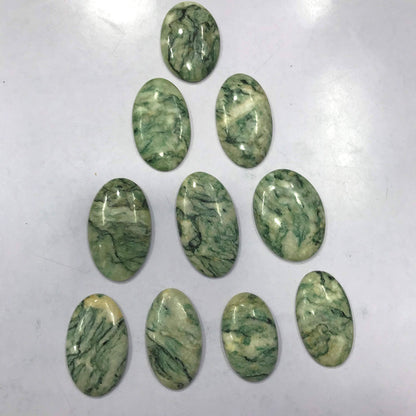 Hand holding natural polished Mariposite cabochons 20 to 35mm size wholesale gemstone lot