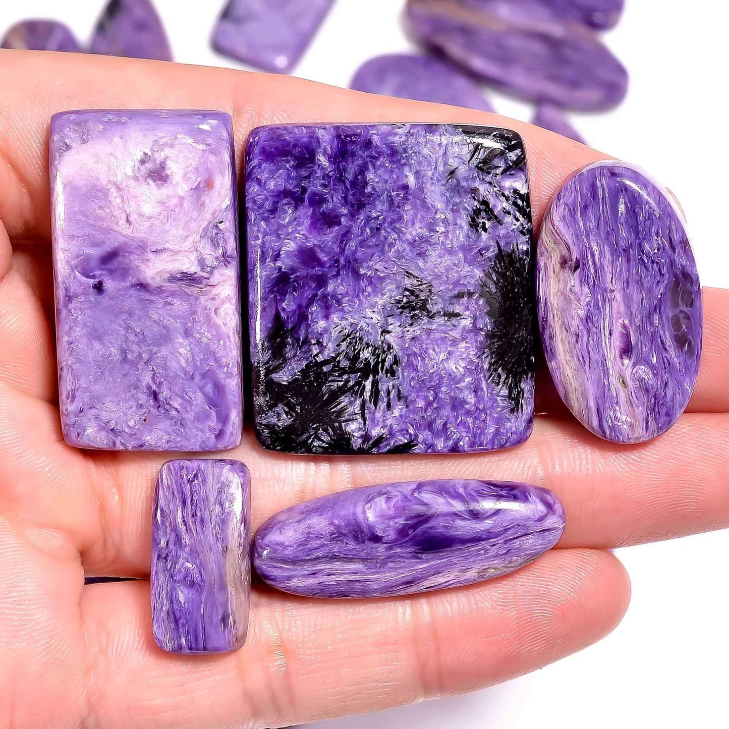 Charoite cabochon held in hand for size and color reference

