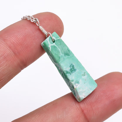 Close-up of a natural green variscite raw stone pendant held in hand highlighting its unique bar shape and healing crystal texture