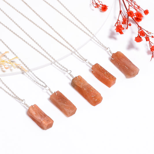 Natural sunstone pendant necklace with raw orange gemstone bar on silver-plated chain in close-up view