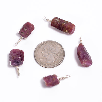 Raw ruby crystal bar pendants shown with a coin for size reference highlighting natural pink color and AA+ quality texture