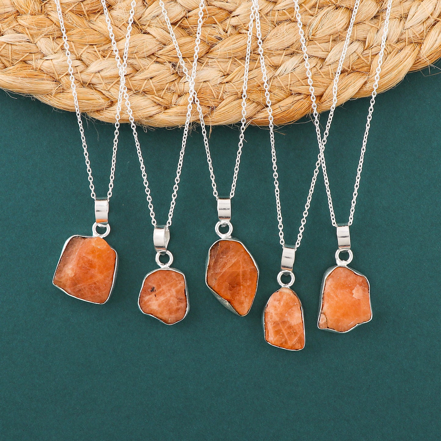 Natural triplite raw crystal pendant necklaces arranged in a row with orange rough stones in bezel settings on silver chain