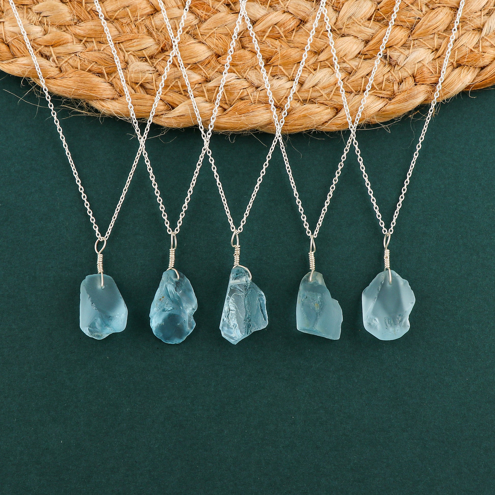 Sky blue topaz raw crystal pendant necklaces arranged in a row showing irregular gemstone shapes on silver-plated chains