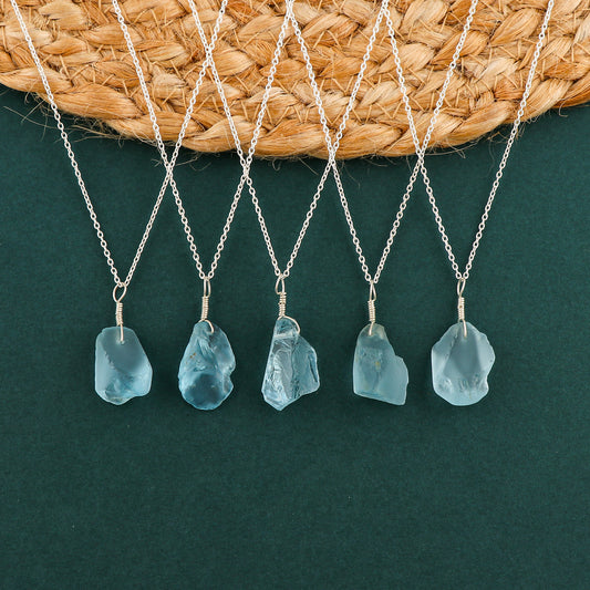 Sky blue topaz raw crystal pendant necklaces arranged in a row showing irregular gemstone shapes on silver-plated chains