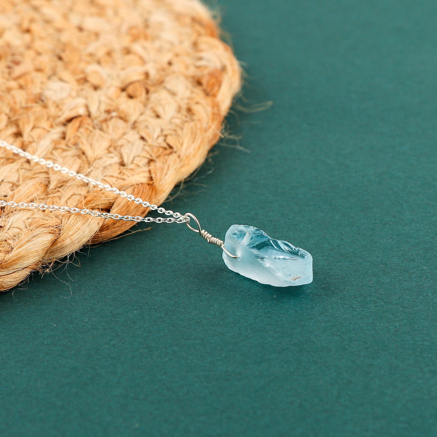 Raw sky blue topaz gemstone pendant displayed against a white background with silver-plated chain and natural rough cut
