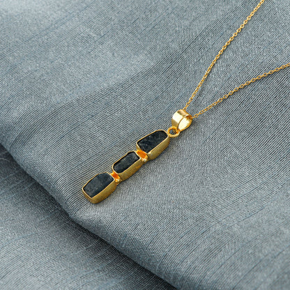 Close-up view of natural sapphire raw gemstone pendant with irregular cut set in gold bezel on 18-inch chain