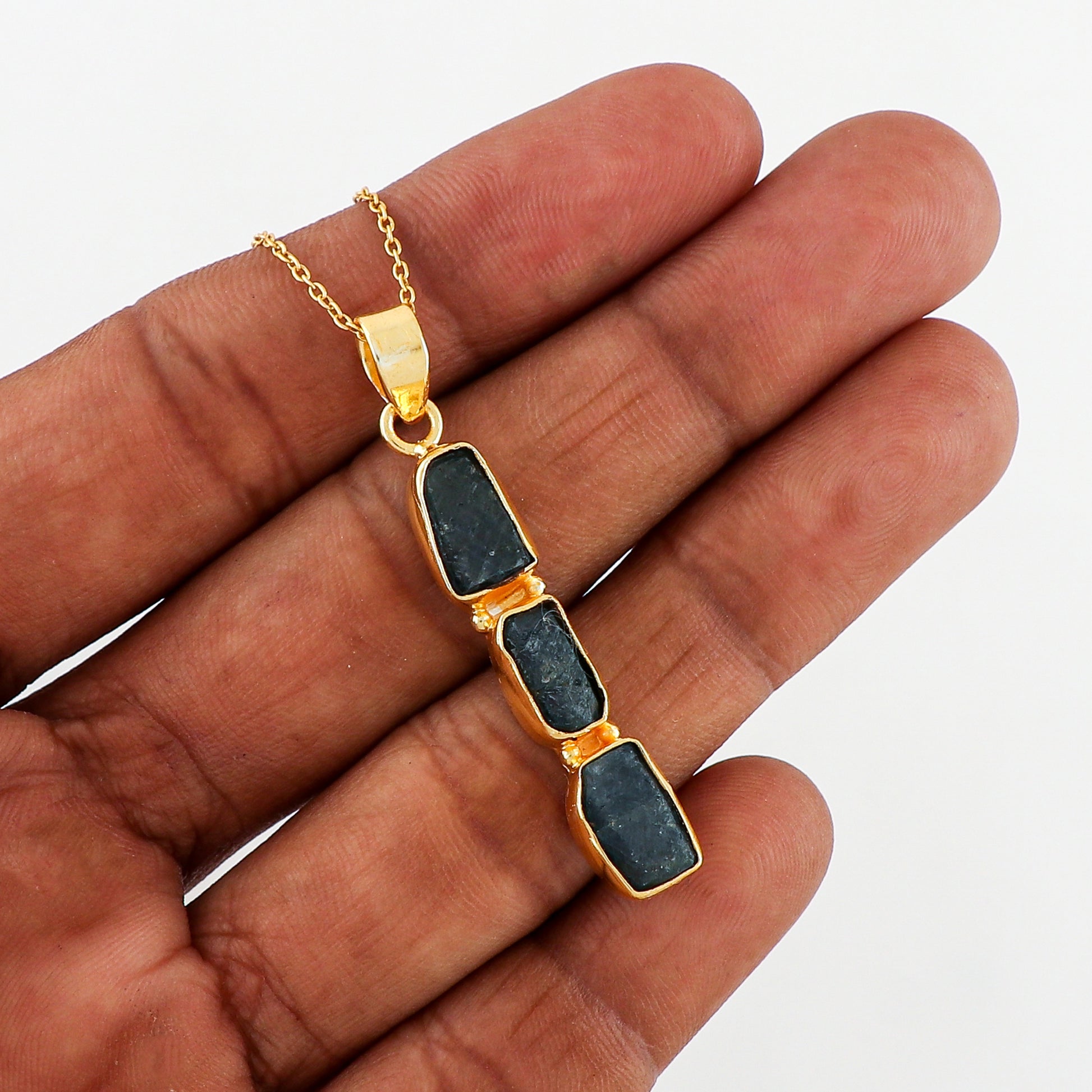 Raw sapphire crystal pendant placed on soft fabric background showcasing rich blue hues and elegant gold-plated finish