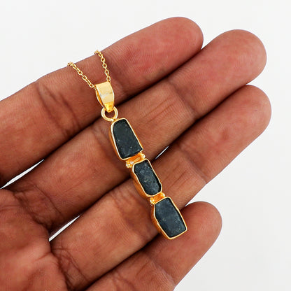 Raw sapphire crystal pendant placed on soft fabric background showcasing rich blue hues and elegant gold-plated finish