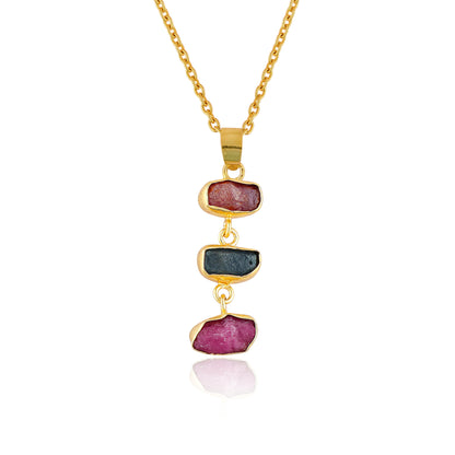 Raw sapphire and ruby crystal pendant necklace in gold-plated bezel displayed on white background showing vibrant blue and pink gemstones