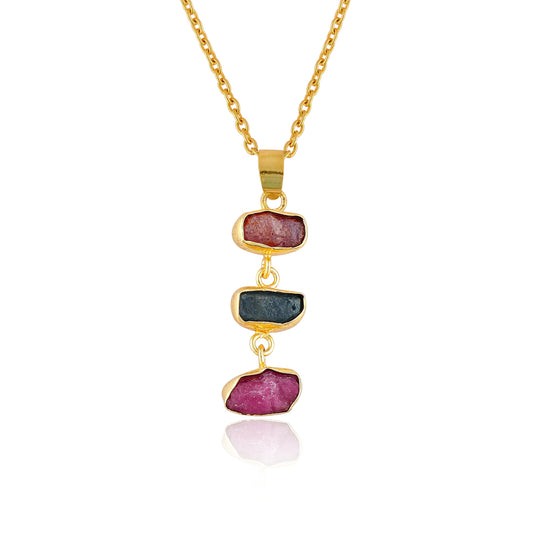 Raw sapphire and ruby crystal pendant necklace in gold-plated bezel displayed on white background showing vibrant blue and pink gemstones
