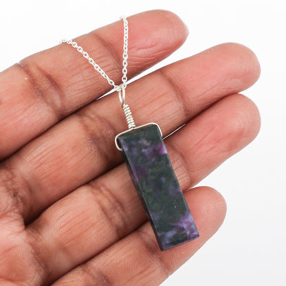 Hand holding a necklace with a rectangular pendant