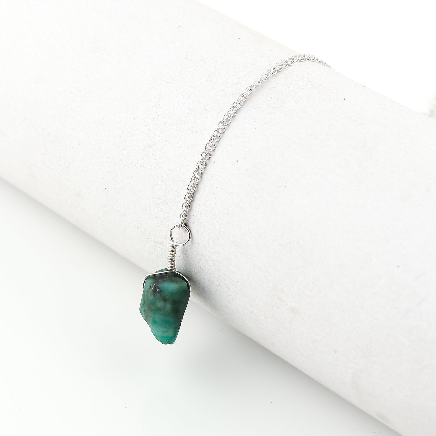Natural raw emerald crystal pendant necklaces arranged in a row showing vibrant green irregular stones on silver-plated 18-inch chains