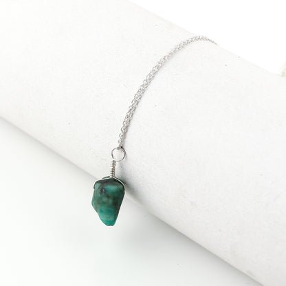 Natural raw emerald crystal pendant necklaces arranged in a row showing vibrant green irregular stones on silver-plated 18-inch chains