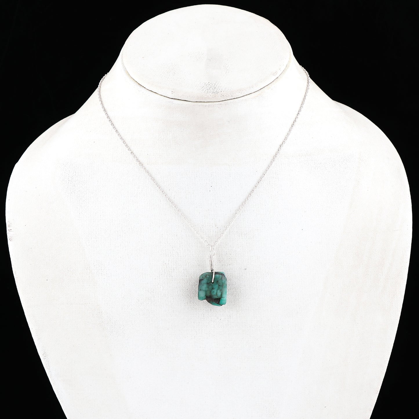 Green pendant necklace on a mannequin with a black background