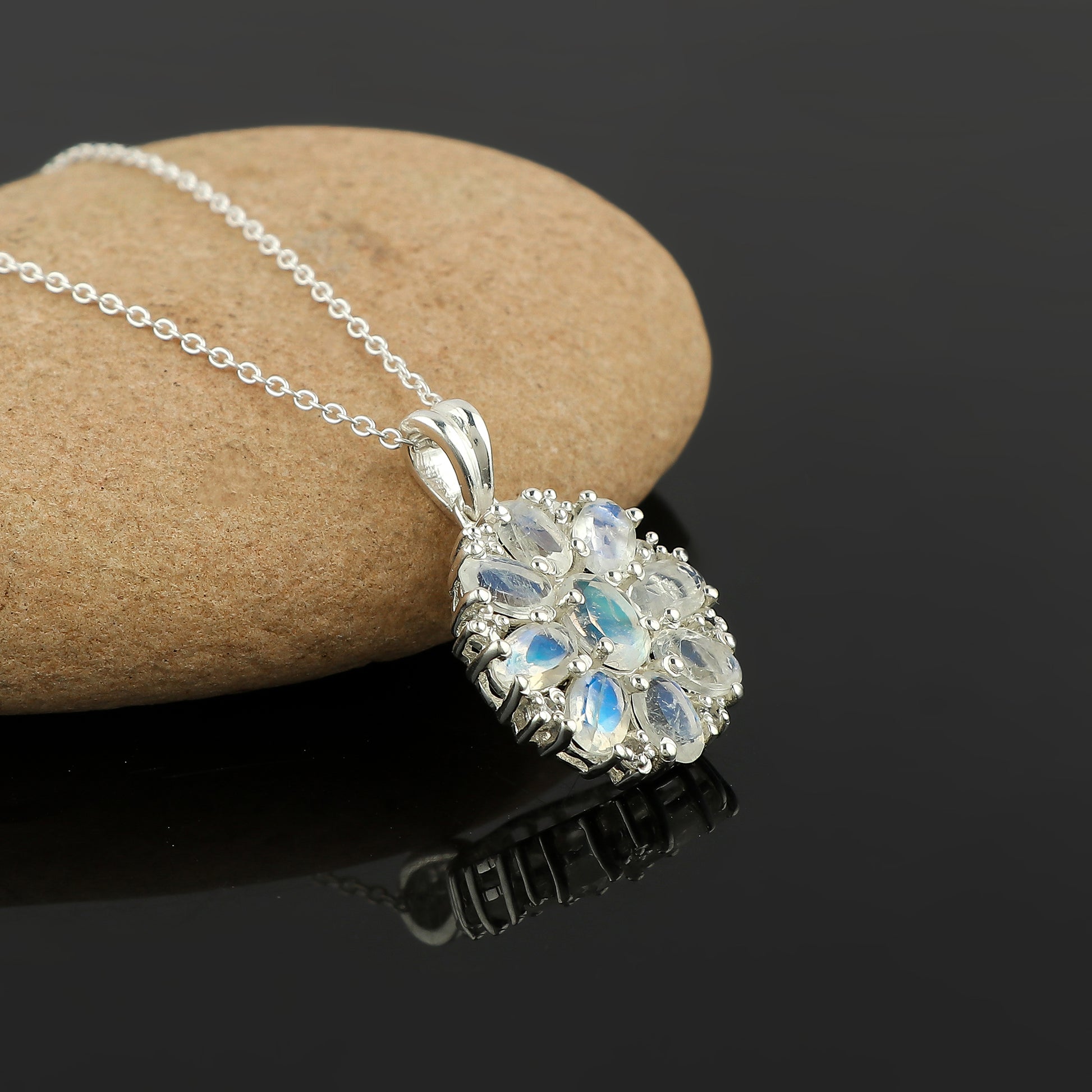 Silver necklace with a floral pendant on a dark surface