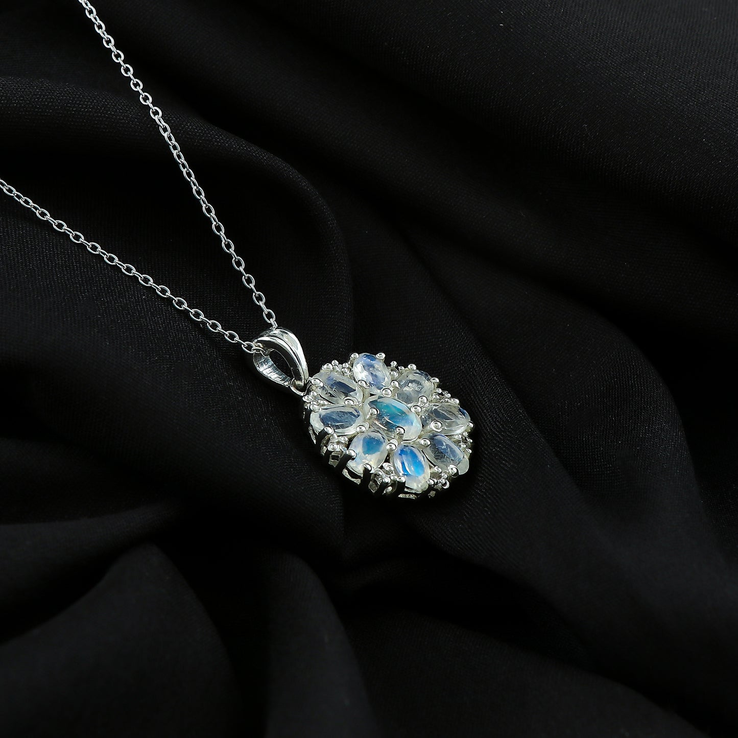 Silver necklace with a floral pendant on a black fabric background