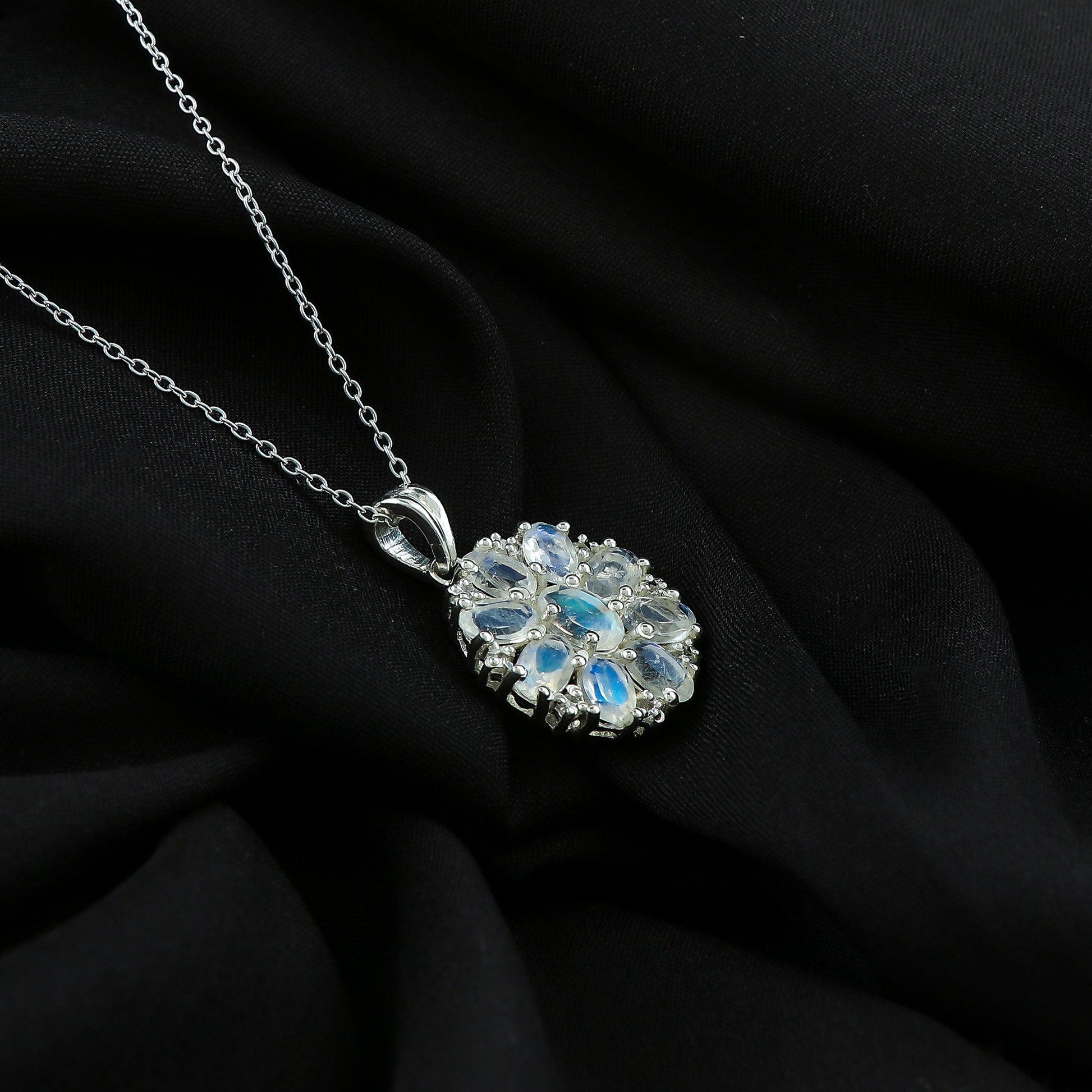 Silver necklace with a floral pendant on a black fabric background