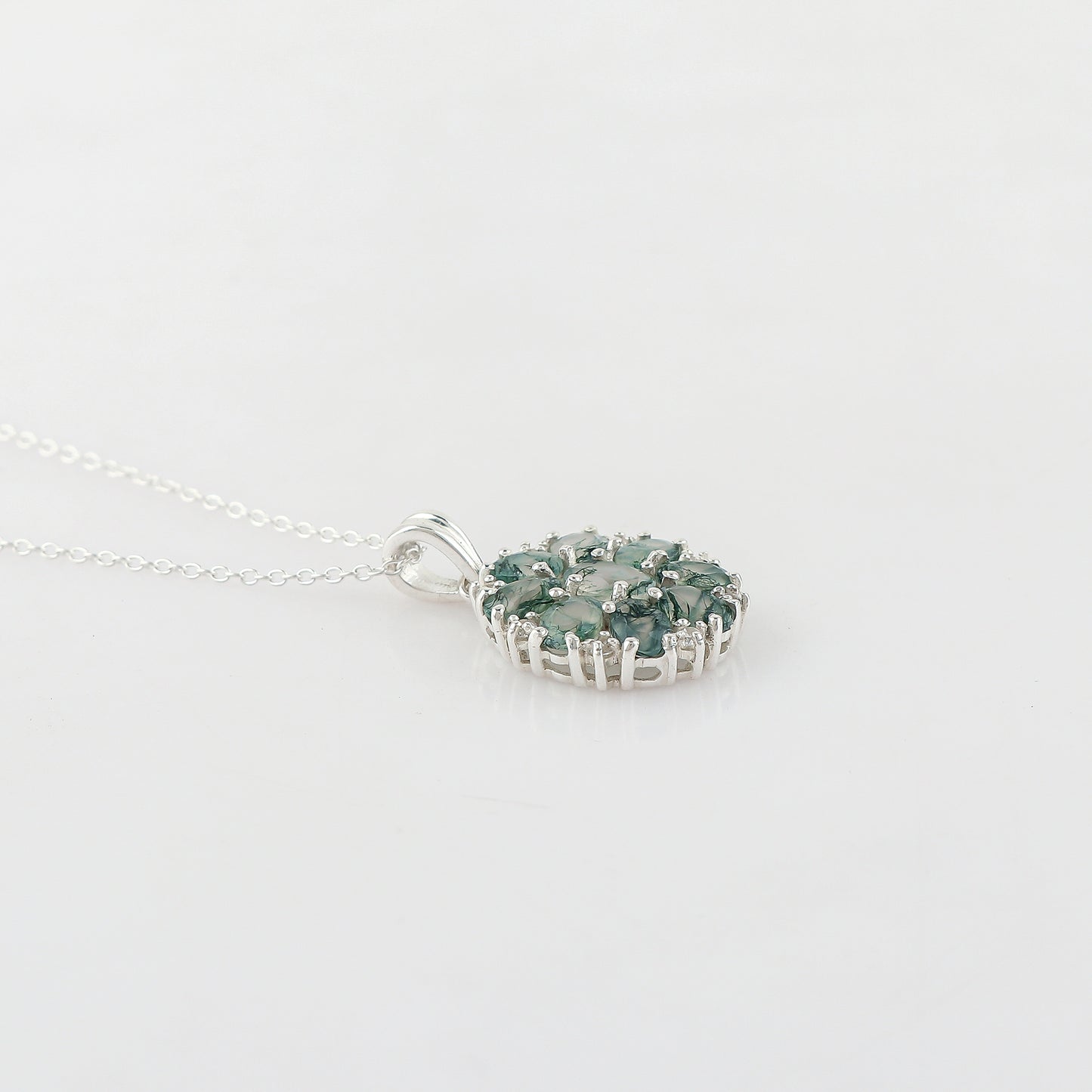 Silver necklace with a green gemstone pendant on a light gray background