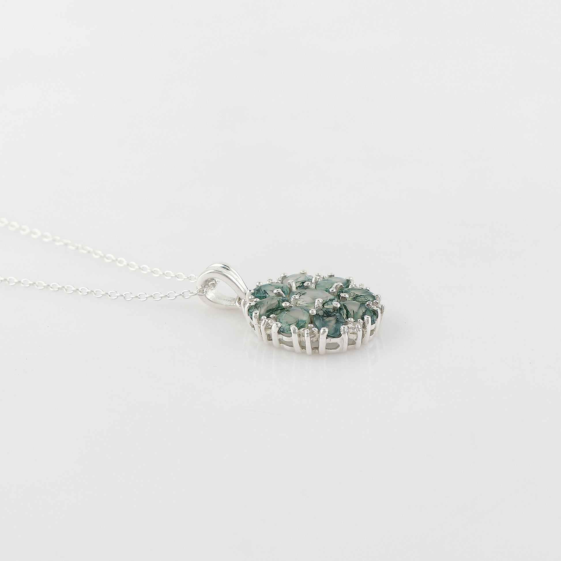 Silver necklace with a green gemstone pendant on a light gray background