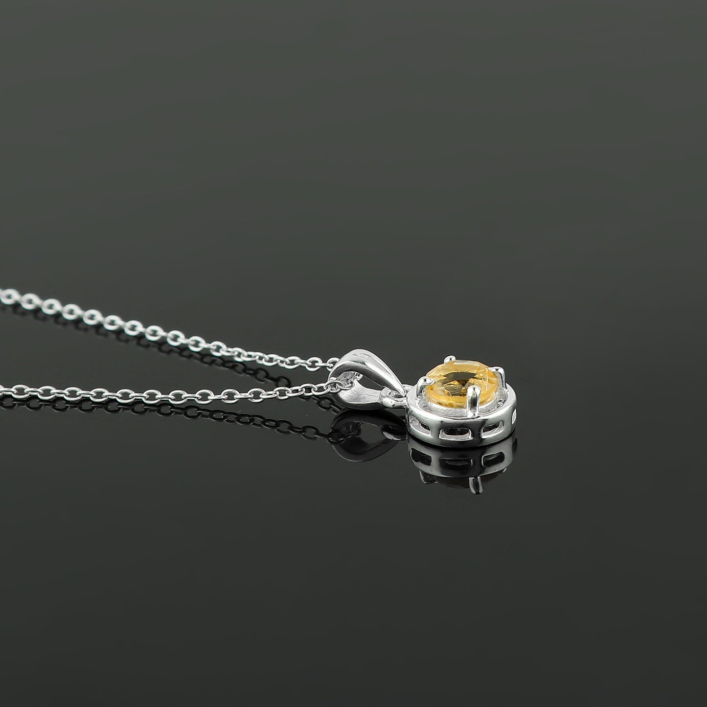 Silver necklace with a yellow gemstone pendant on a black background