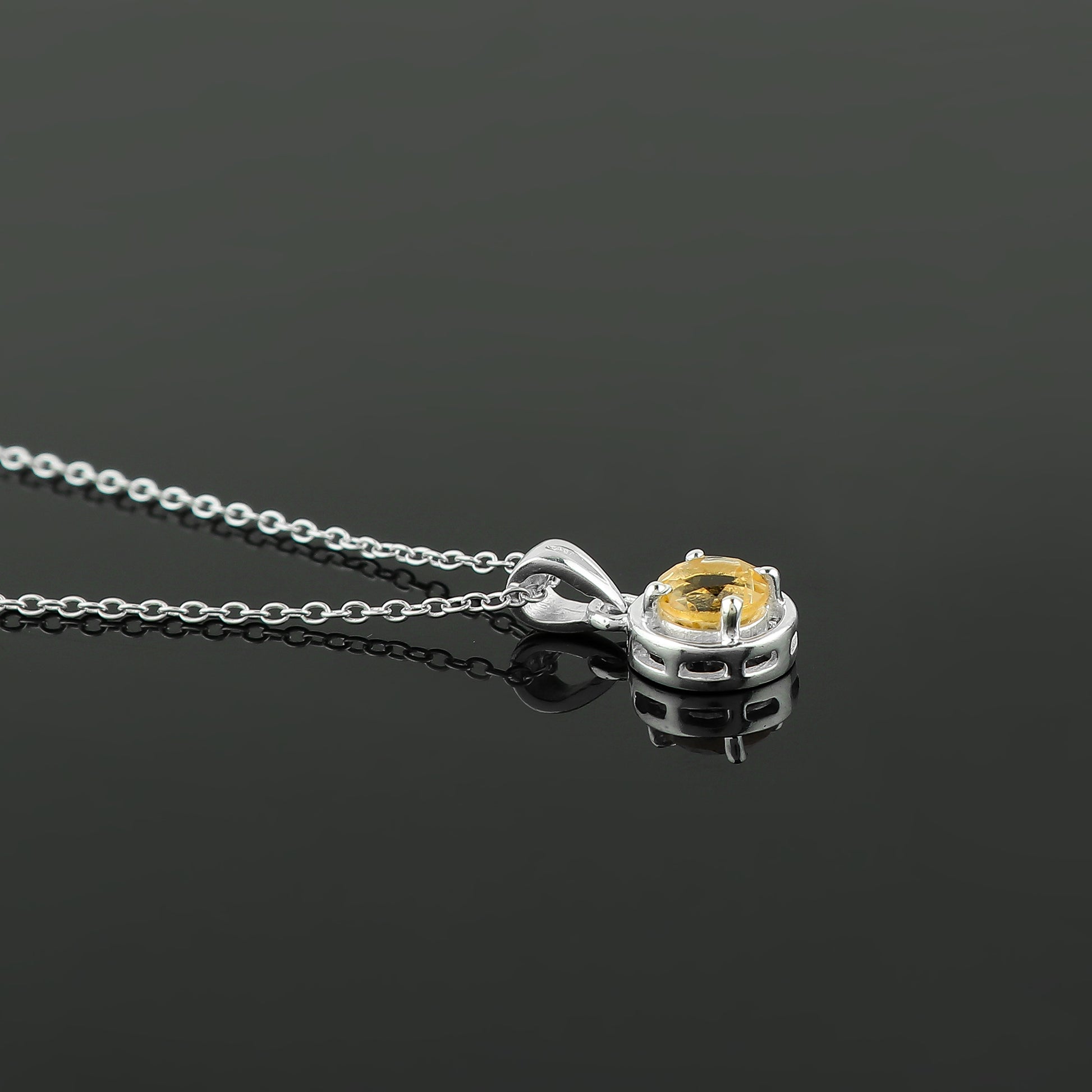 Silver necklace with a yellow gemstone pendant on a black background