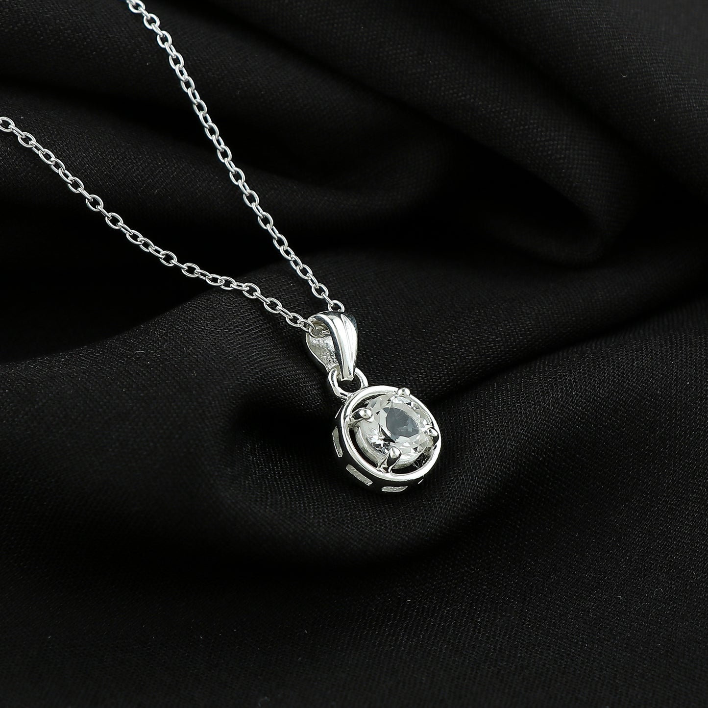 Silver necklace with a pendant on a black fabric background