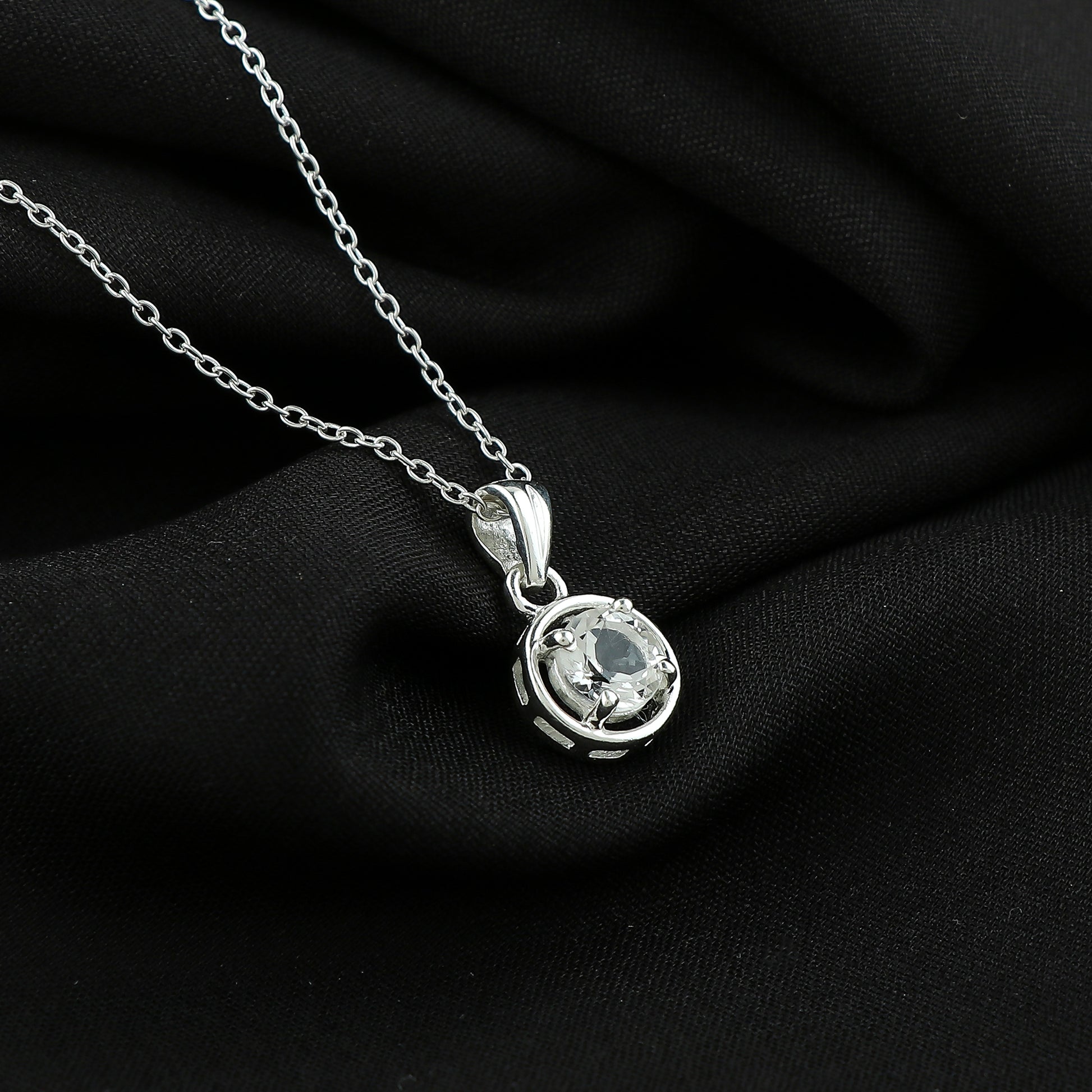 Silver necklace with a pendant on a black fabric background