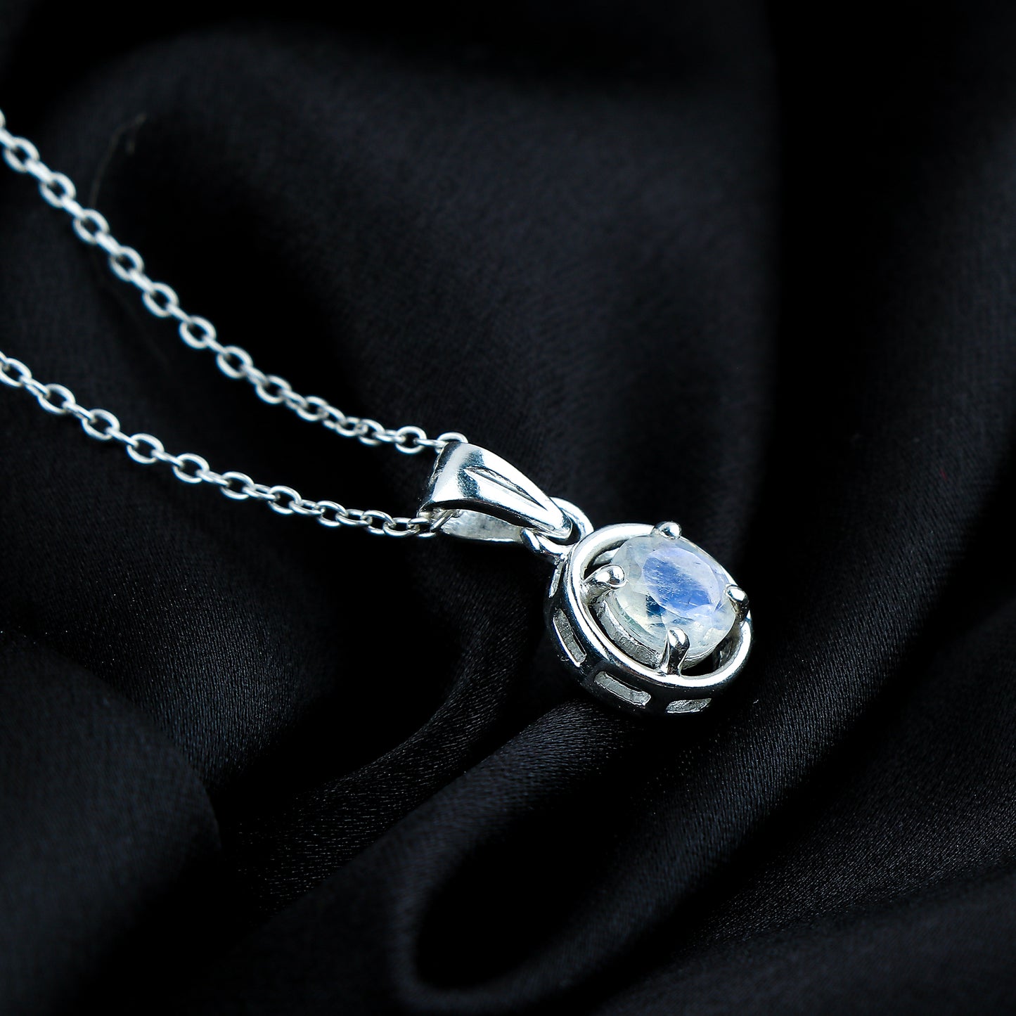 Silver necklace with a pendant on a black fabric background