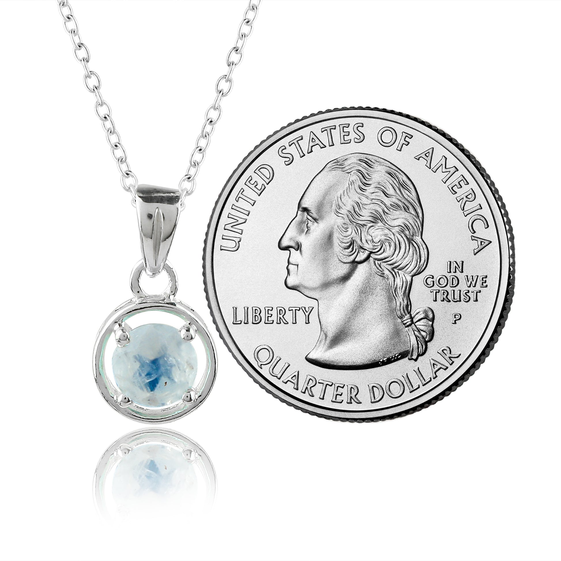 Silver pendant with a blue gemstone next to a U.S. quarter dollar coin on a white background