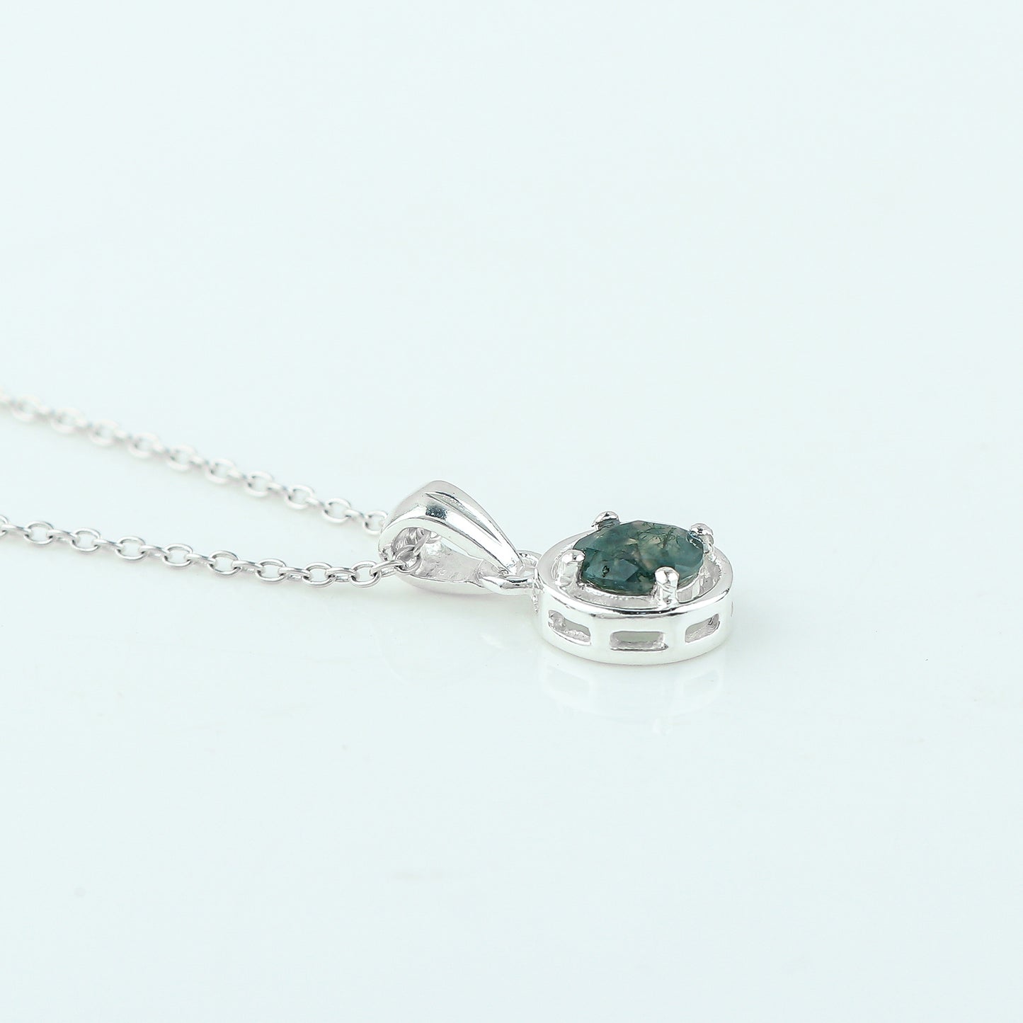 Silver pendant with a green gemstone on a white background