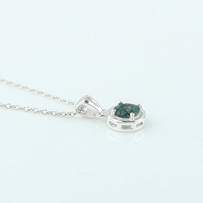 Silver pendant with a green gemstone on a white background