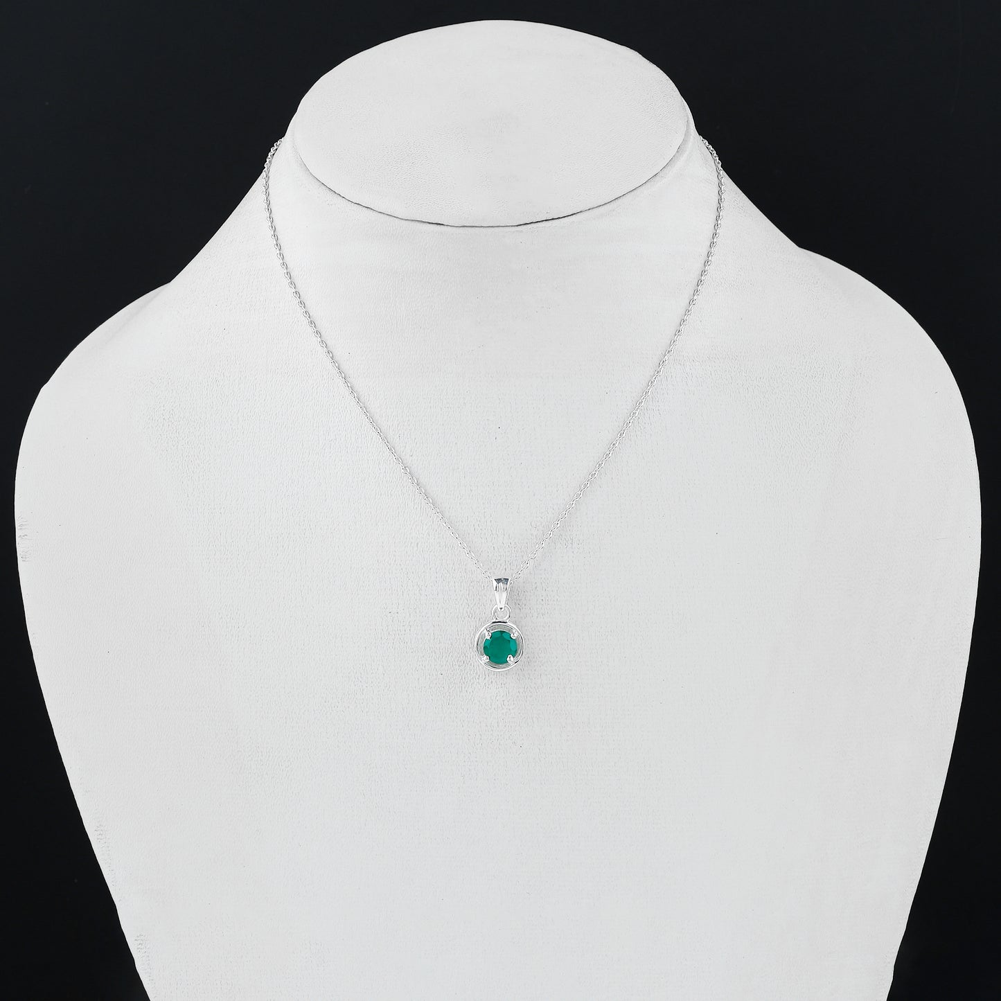 Silver necklace with a green gemstone pendant on a mannequin bust.