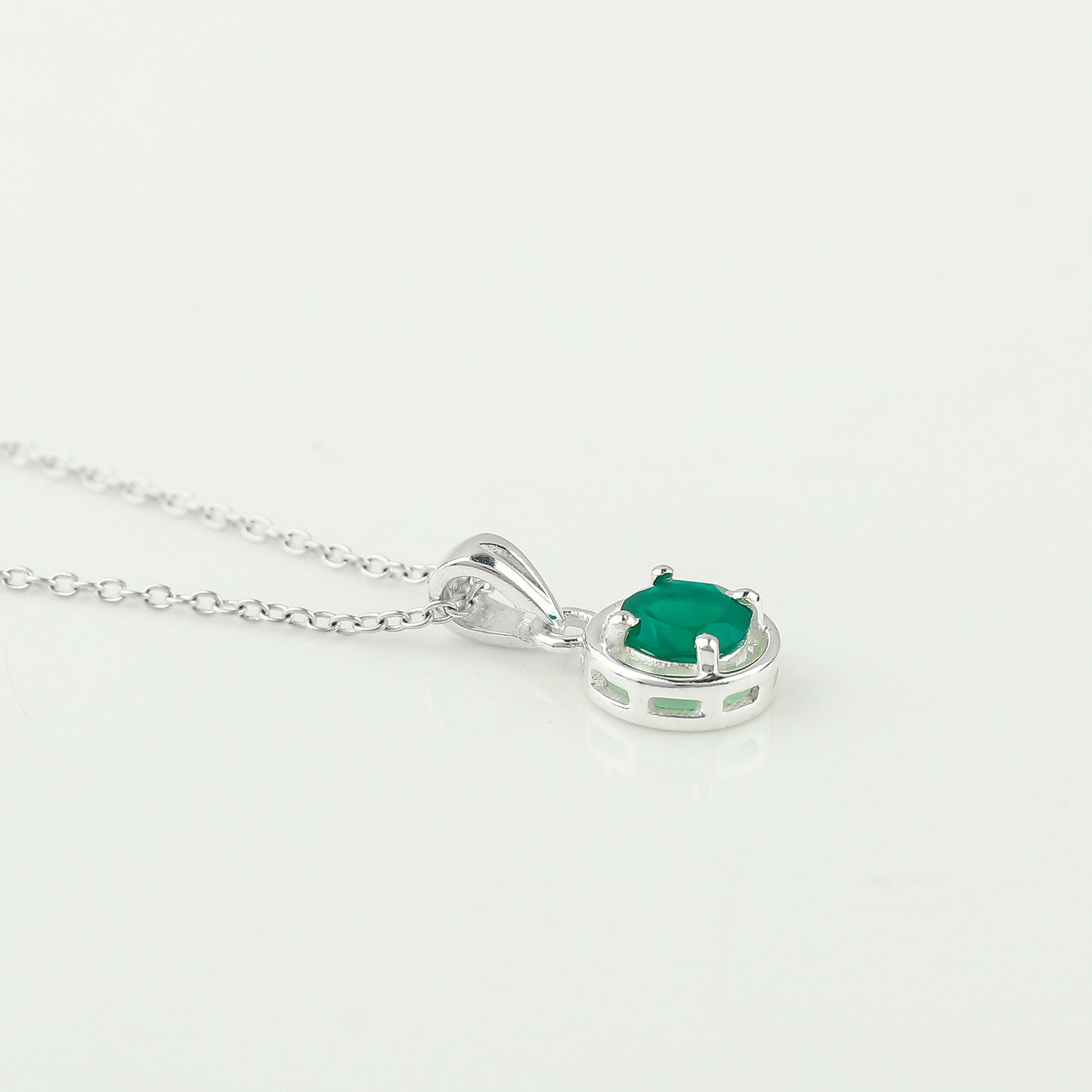 Silver necklace with a green gemstone pendant on a white background