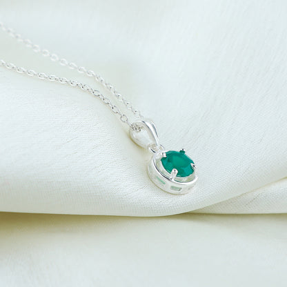Silver necklace with a green gemstone pendant on a white fabric background