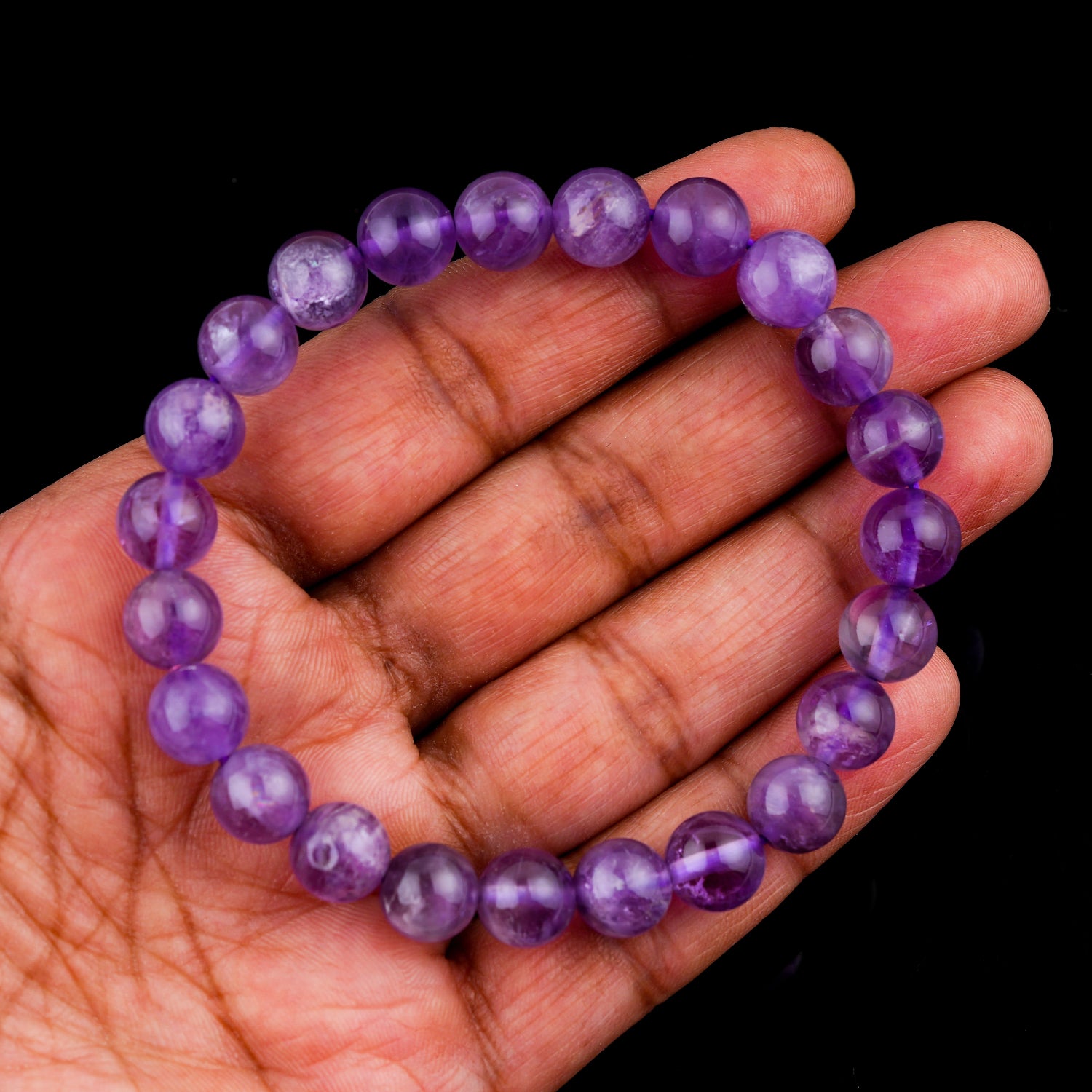Amethyst  Purple beaded bracelet on a hand against a black background