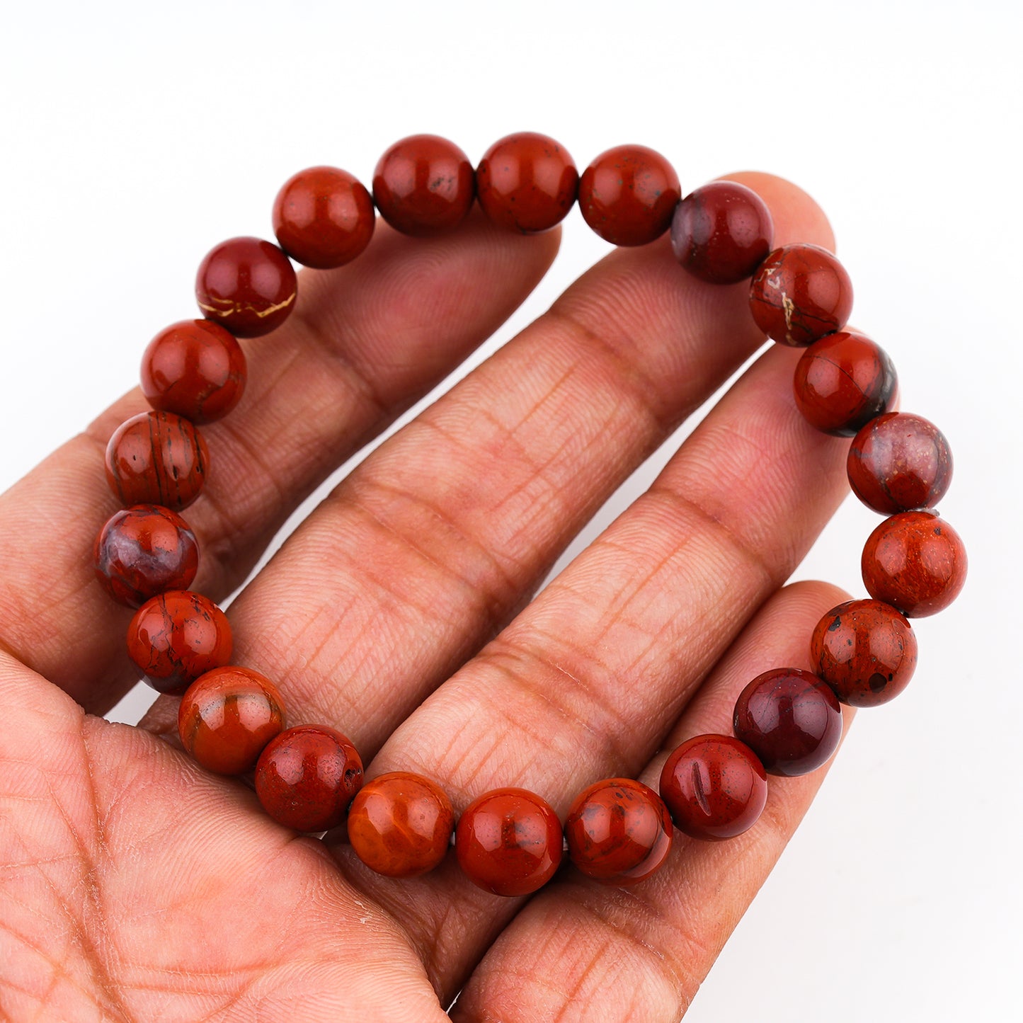 Red beaded bracelet on a hand against a white background
