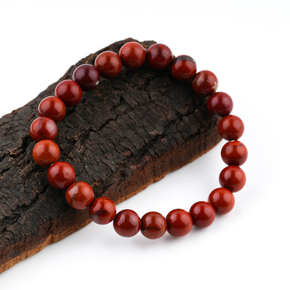 Red Jasper Beaded Bracelet on a wooden surface with a white background