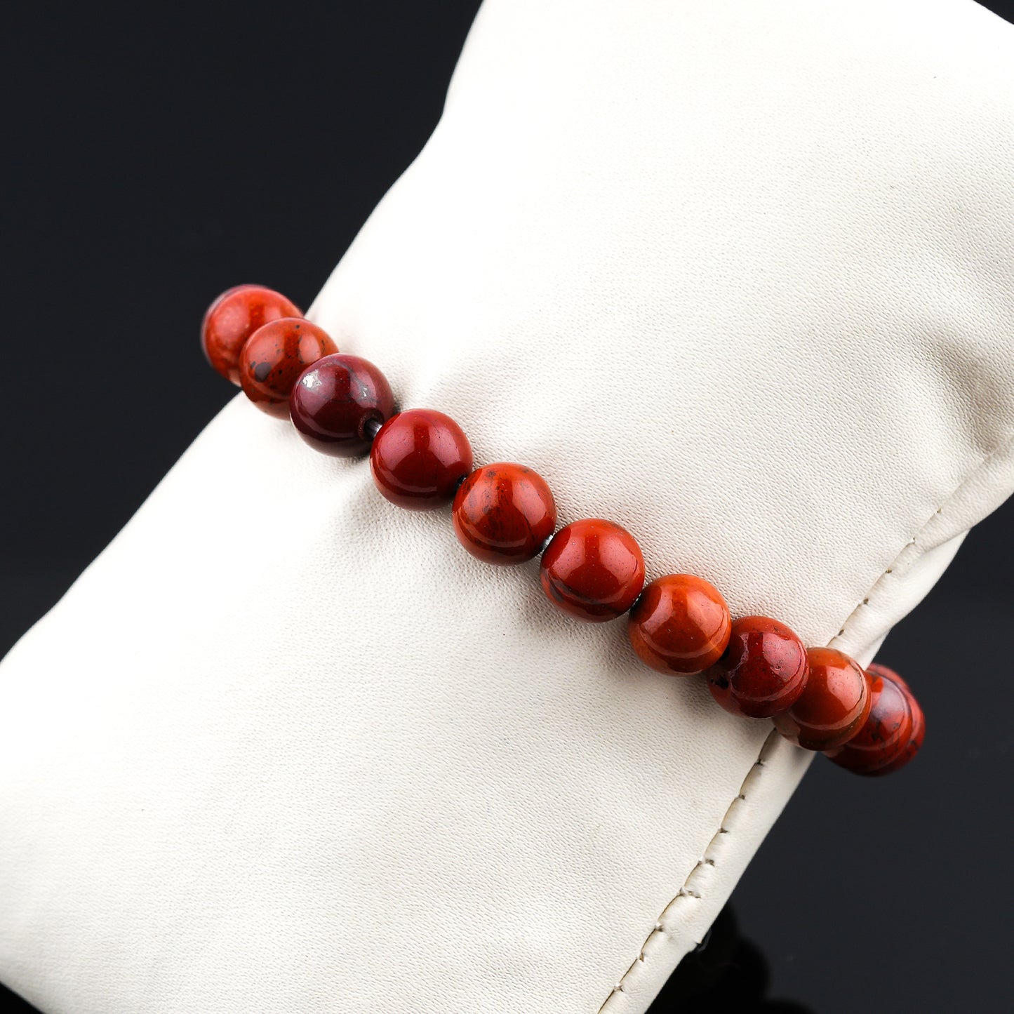 Red beaded bracelet on a white surface with a black background