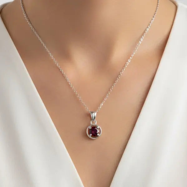 Round cut deep red garnet gemstone pendant in silver bezel setting worn by model